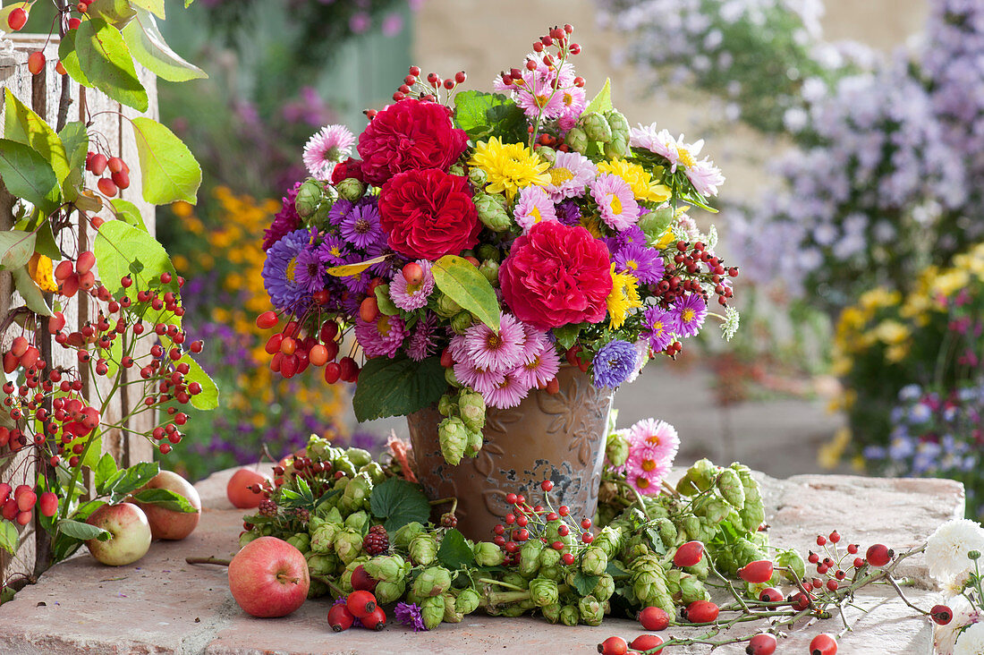 Autumn bouquet with roses, asters, chrysanthemums, hops, rose hips and summer asters in a hop wreath