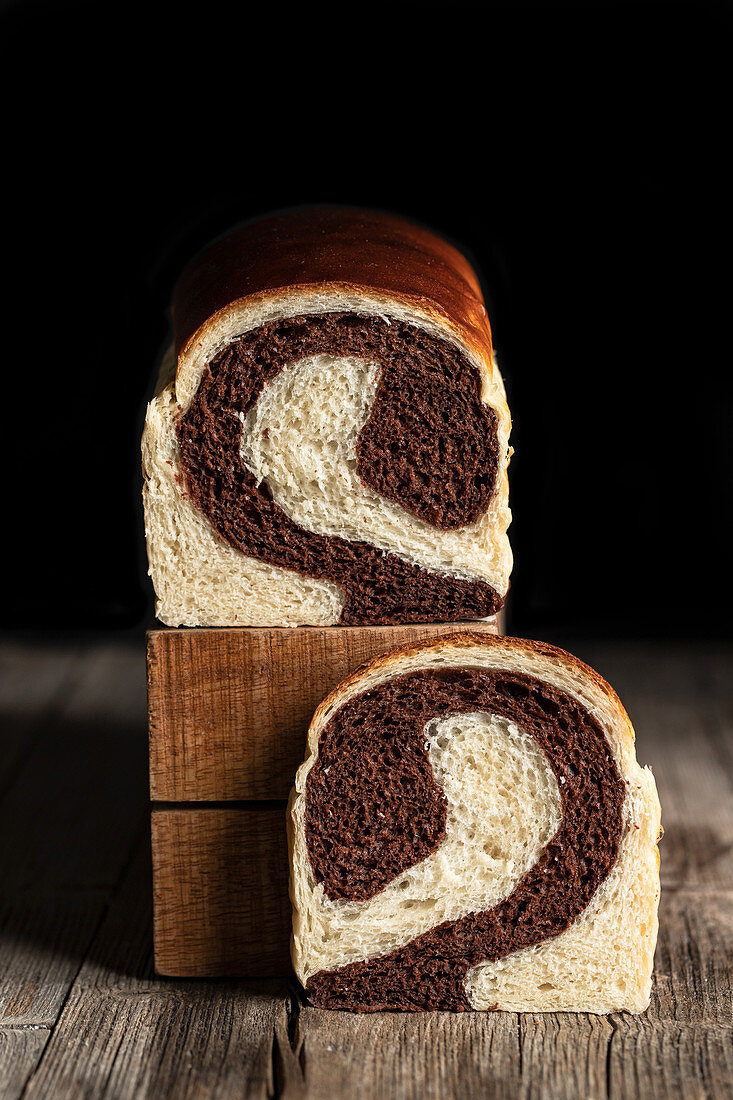 Homemade bread with chocolate and banana flavor placed on wooden table in kitchen on black background