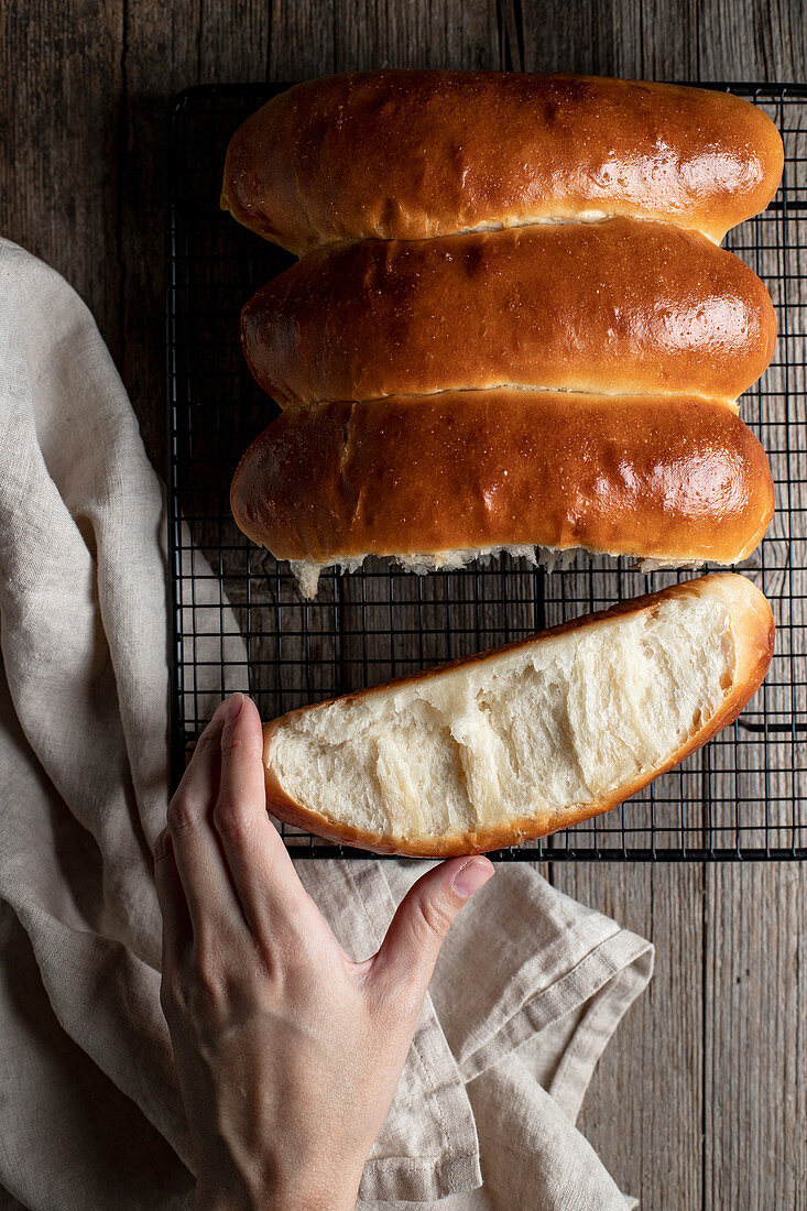 Hand greift nach Hot-Dog-Brötchen