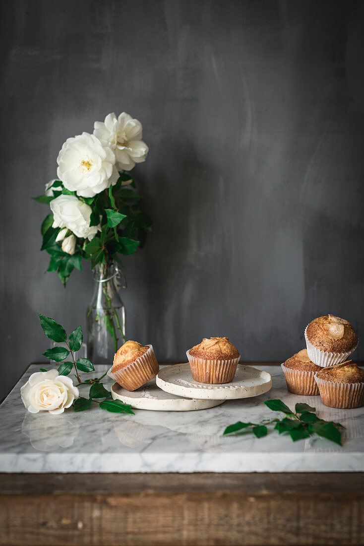 Joghurt-Cupcakes und weiße Rosen in Glasvase