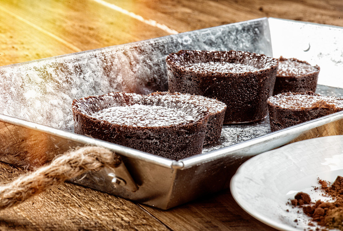Rustic metal tray with chocolate coulants sprinkled lightly with icing sugar