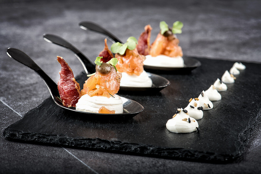 smoked salmon and meat slices placed on slate board with cream cheese