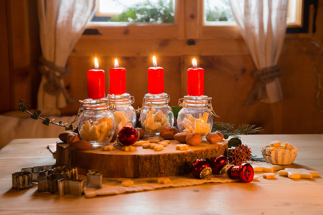 Advent arrangement of four red candles on top of swing-top jars of biscuits