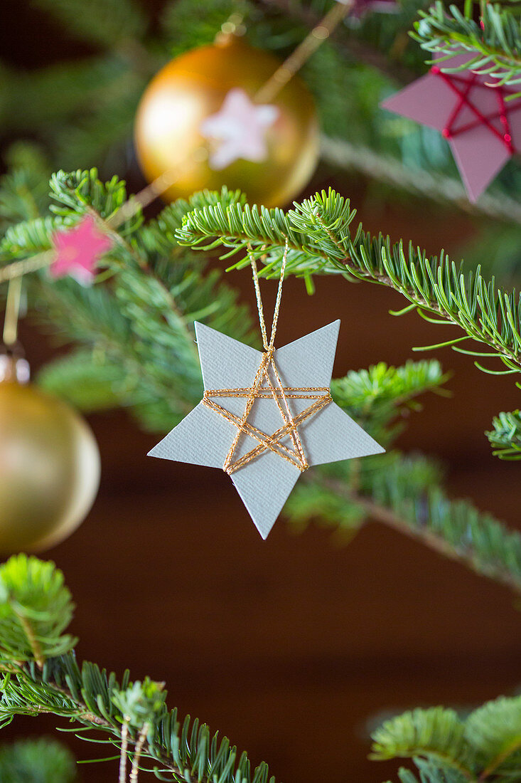 Selbstgemachter Christbaumanhänger aus mit Garn umwickeltem Papier