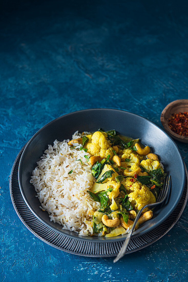Vegan indian cauliflower and cashewnut curry with spinach and rice