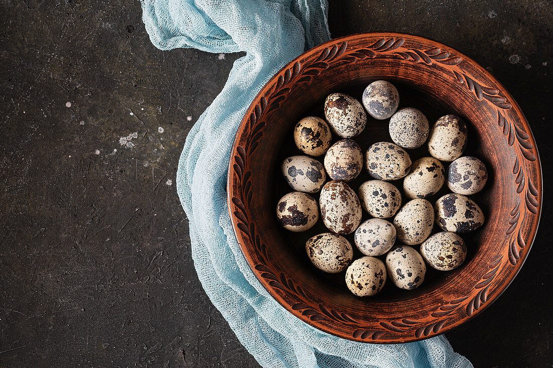 Quail eggs in a clay bowl with blue cheesecloth