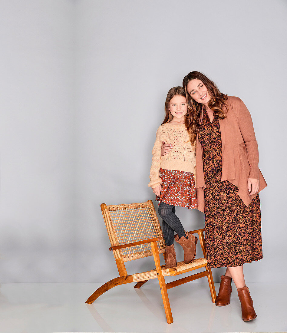A mother and daughter wearing similar outfits in shades of brown