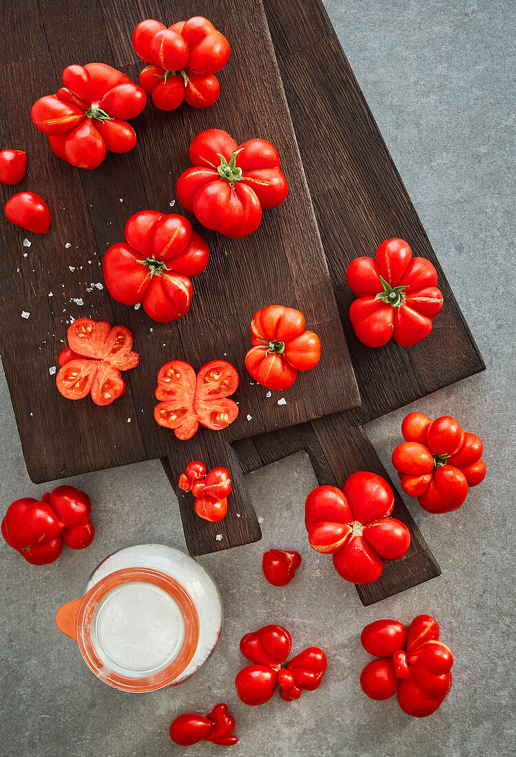 Tomatoes on a dark cutting board with coarse sea salt