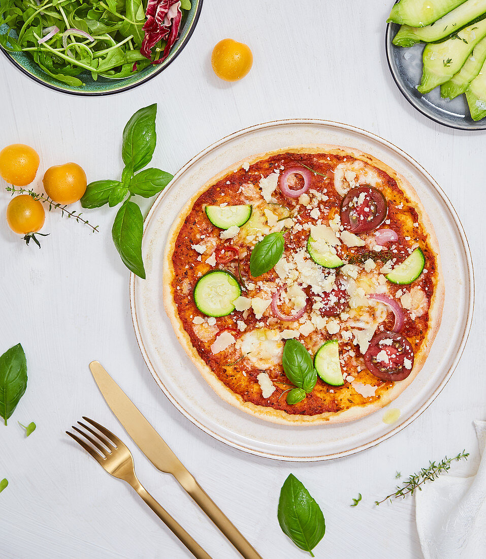 Pizza mit Zucchini, Tomaten, Oregano, Basilikum und Parmesan