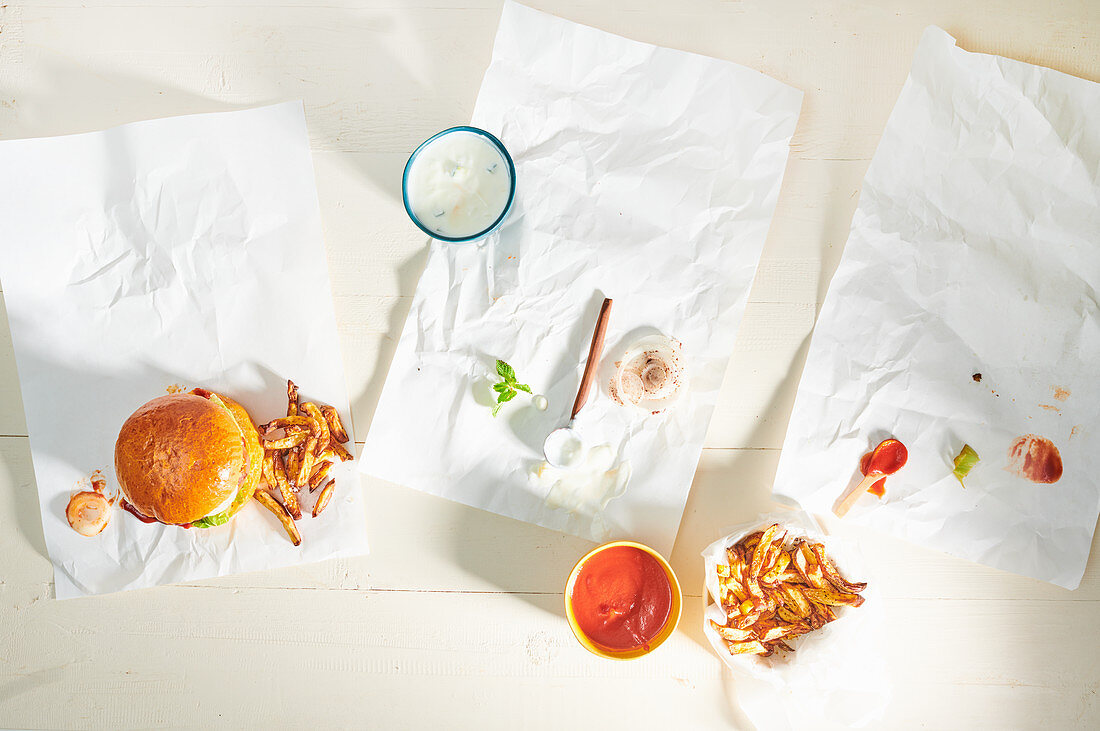 Burger mit Pommes Frites und Essensreste auf Papier