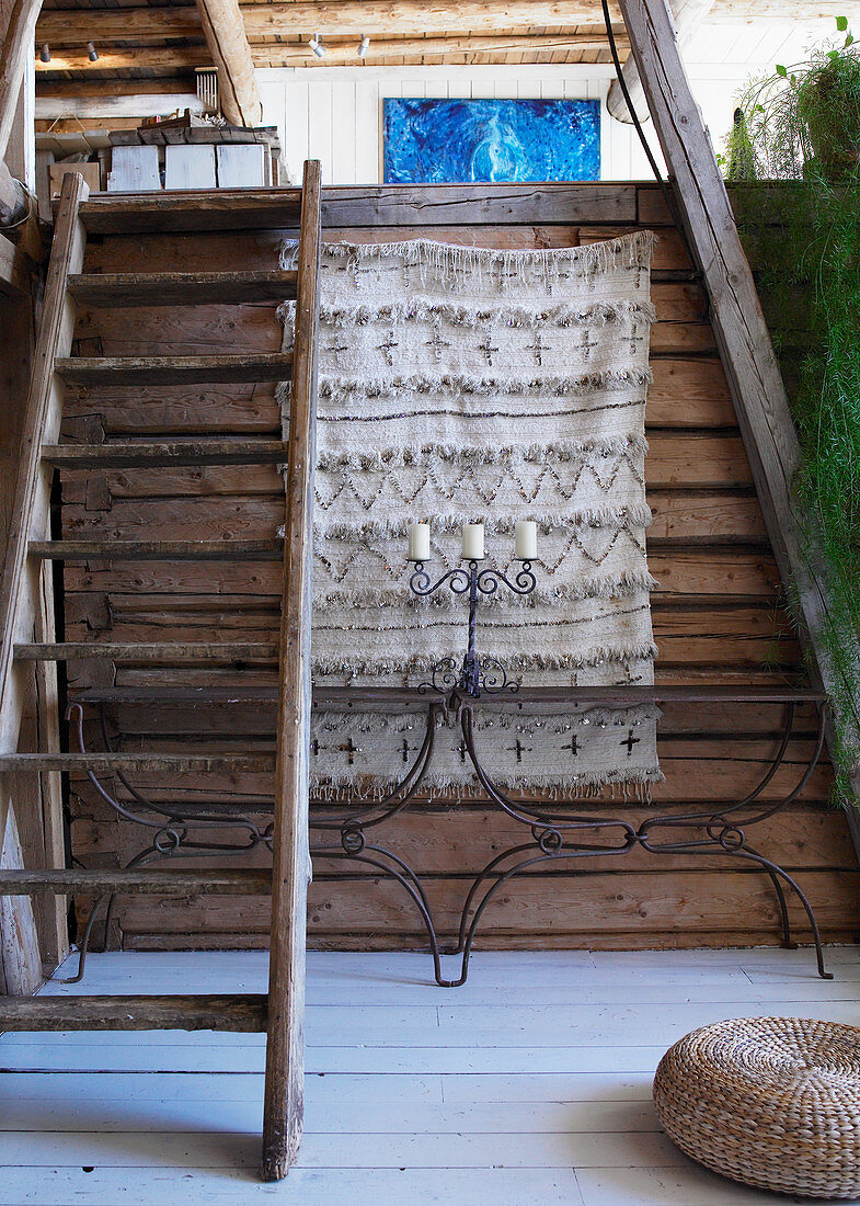 Two metal console tables against rustic wooden wall below steps