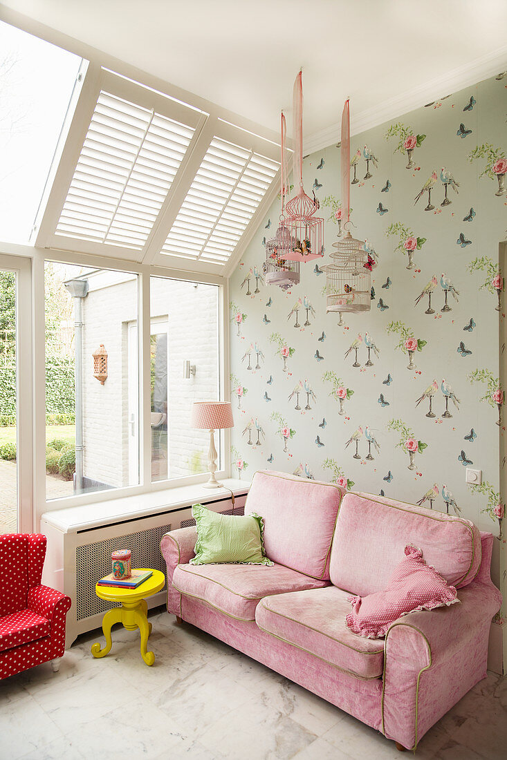 Pink sofa against wallpaper with bird motif in girl's bedroom