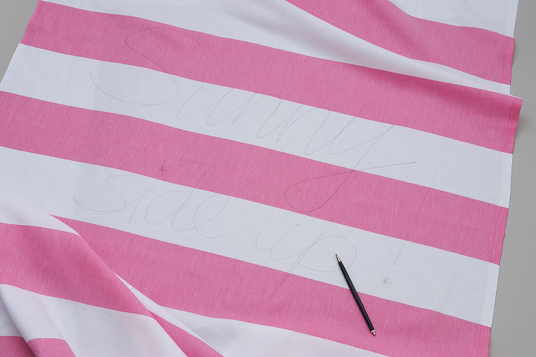 Pink-and-white striped cloth and darning needle