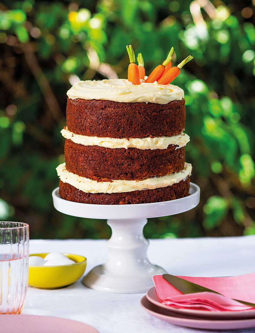 Multi-tiered carrot cake with pineapple and rum on an outdoor table