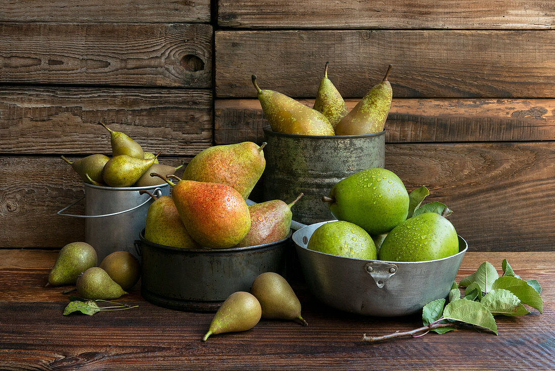 Verschiedene Birnensorten in Vintage-Gefäßen auf Holztisch