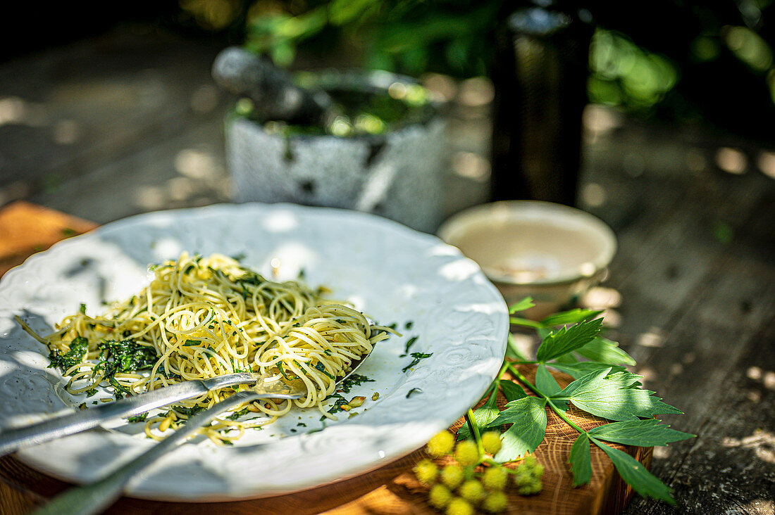 Spaghetti mit Liebstöckel-Pesto auf Tisch im Garten