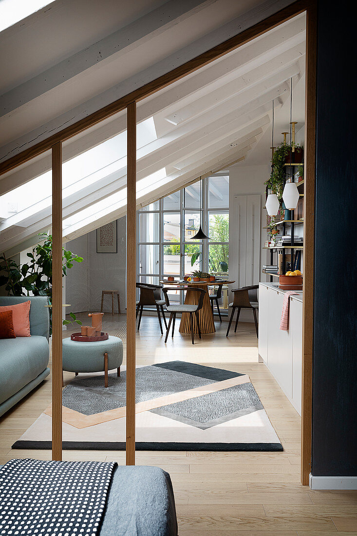 A view from a bedroom into a living room with a sofa, a kitchen and a dining area