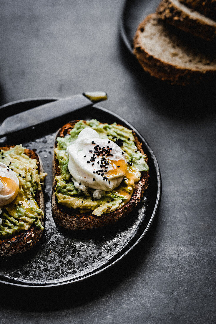 Avocado toast with poached egg sprinkled with black sesame seeds