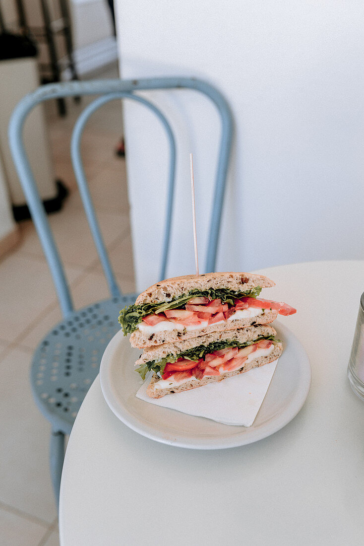 Sandwich mit Mozzarella, Tomaten und Rucola auf Bistrotisch