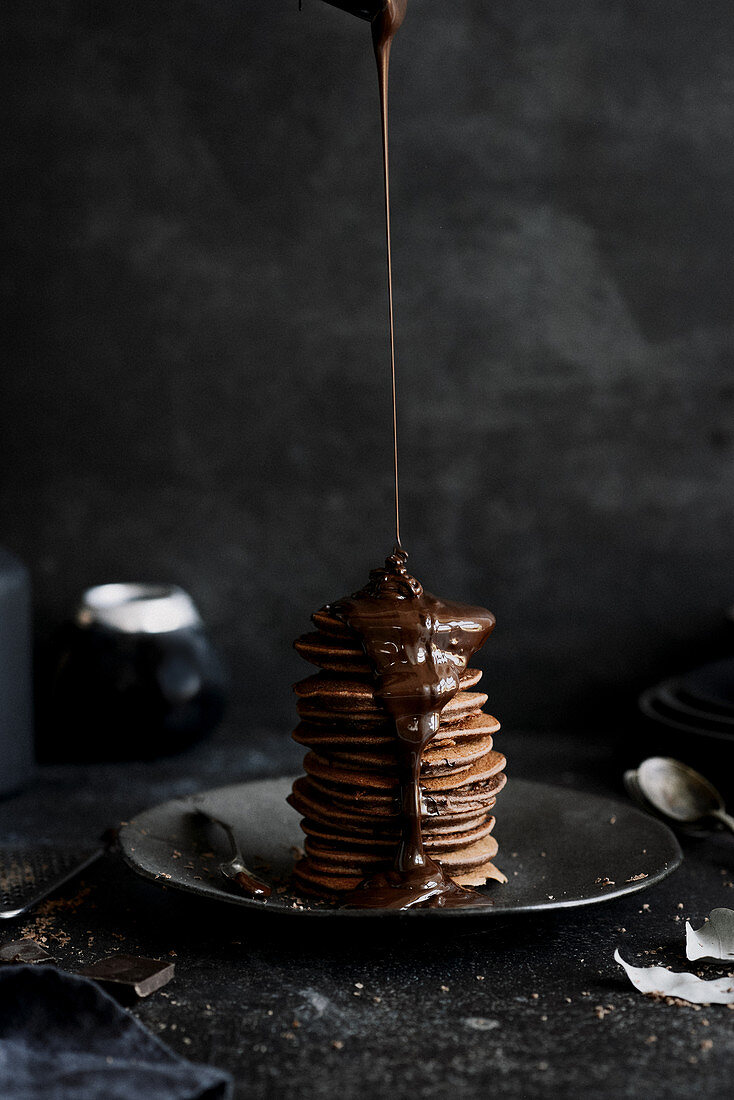 Schokoladen fließt auf einen Stapel Schokoladen-Pancakes