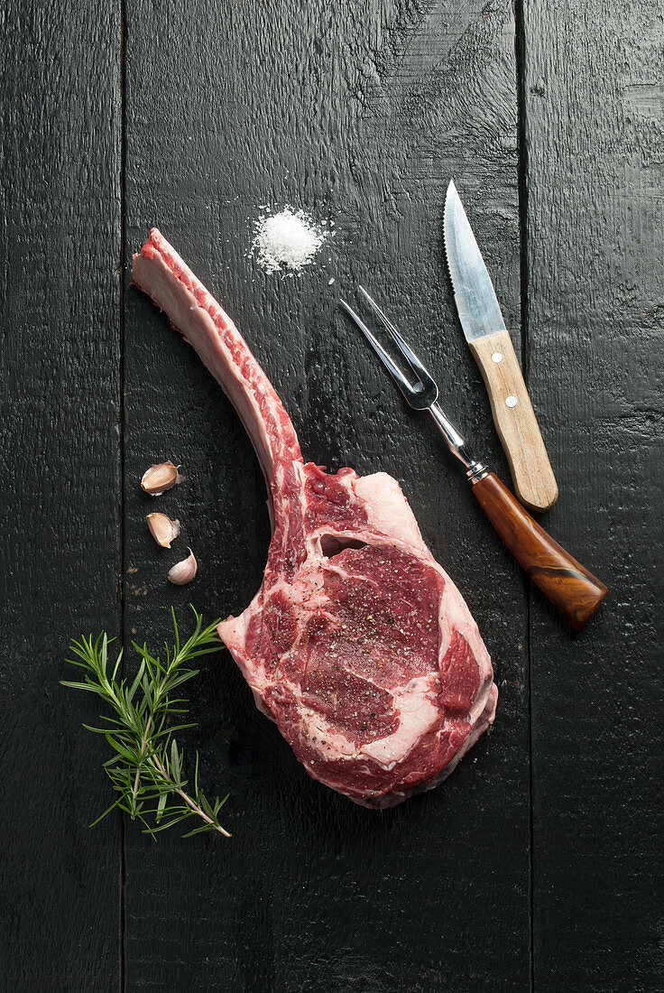 Raw tomahawk steak with rosemary and garlic