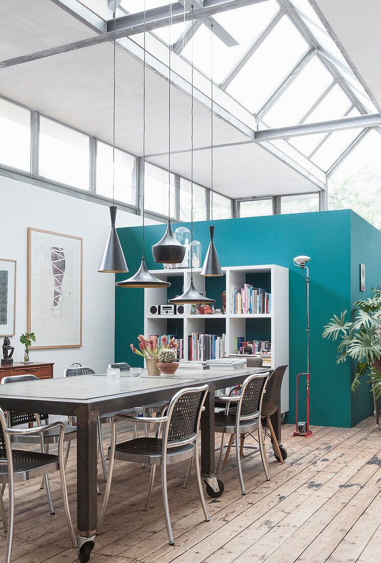 A rollable dining table with chairs and open shelving in a loft apartment