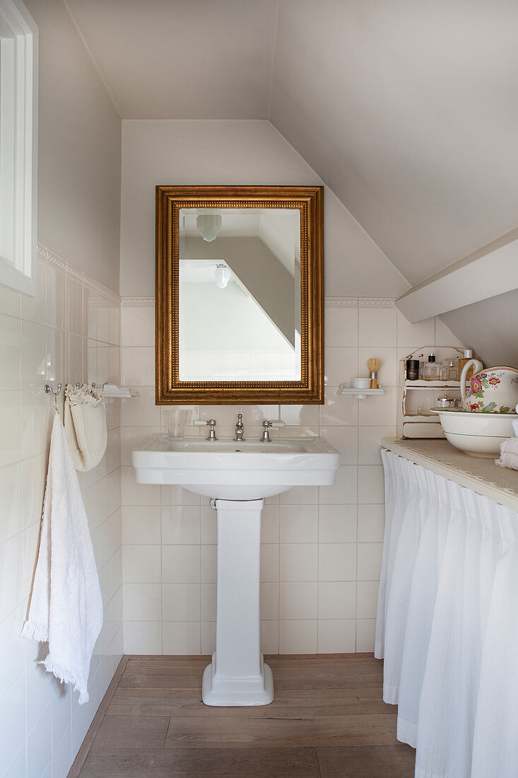 A nostalgic attic bathroom with a gold-framed mirror