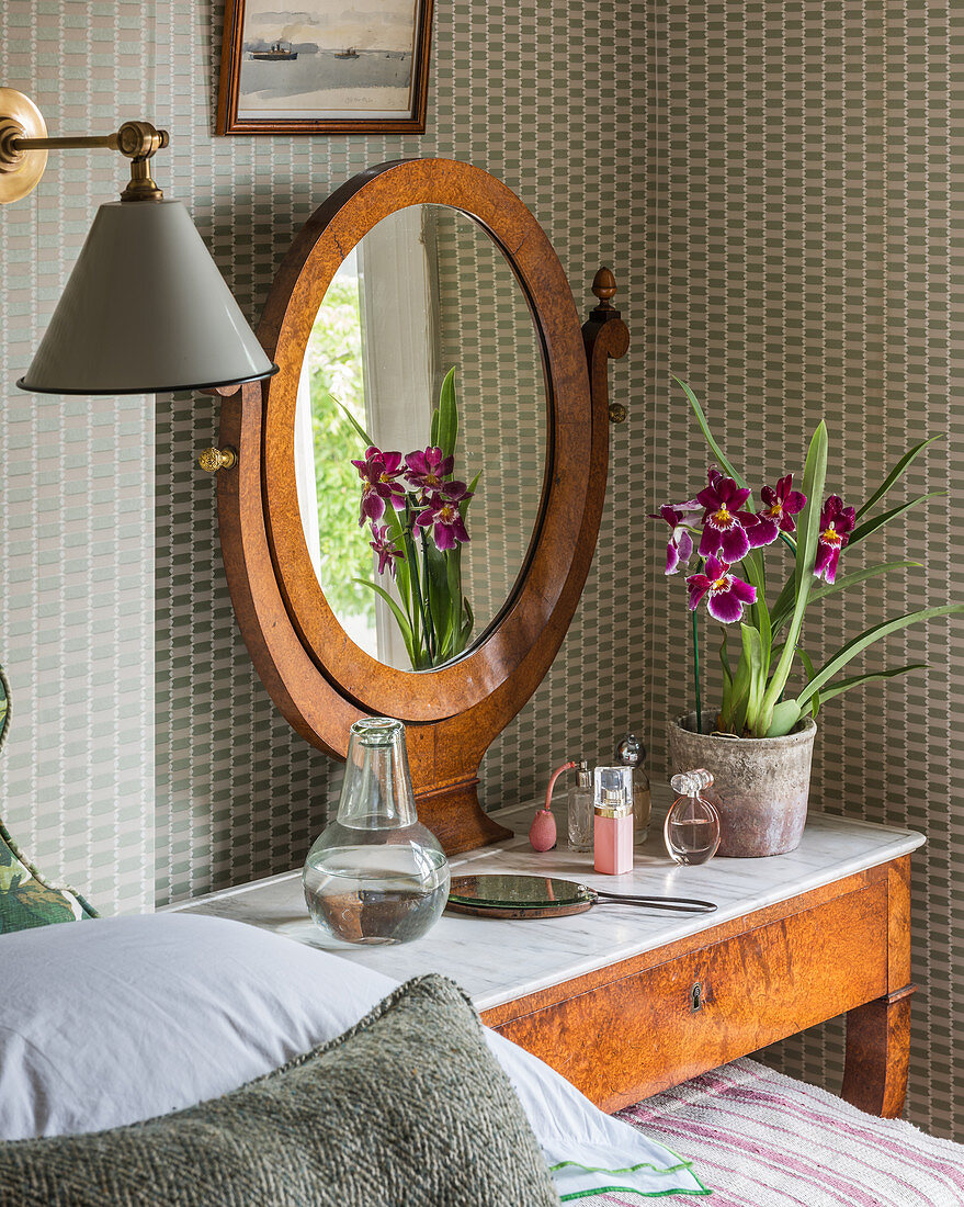 An orchid reflected in a mirror on a dressing table