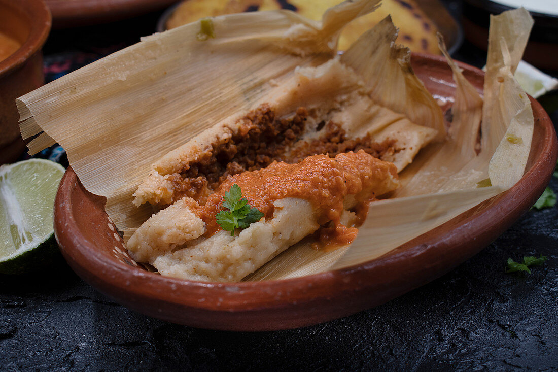 Vegan tamales filled with seitan, masa, chile verde and served with ranchero sauce, cream and chili beans