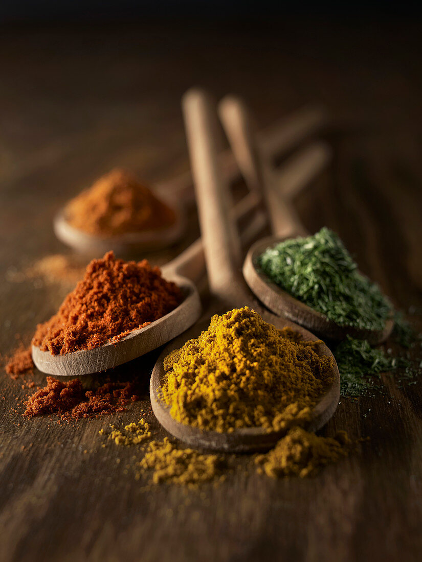 Various spices on wooden spoons