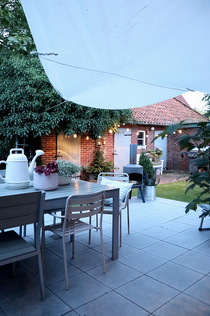 Table and chairs on terrace in courtyard garden at twilight