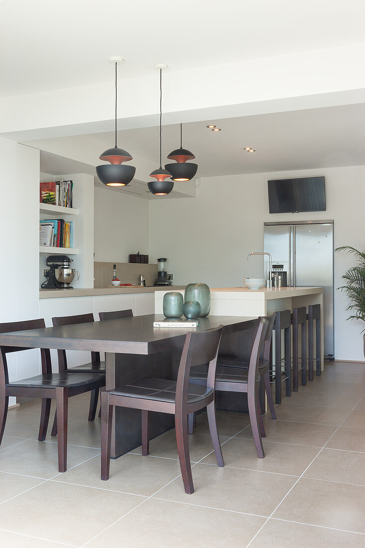 Dark wooden dining table adjacent to kitchen island