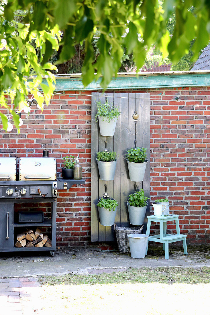 Plants in wall-mounted holder made from boards and buckets