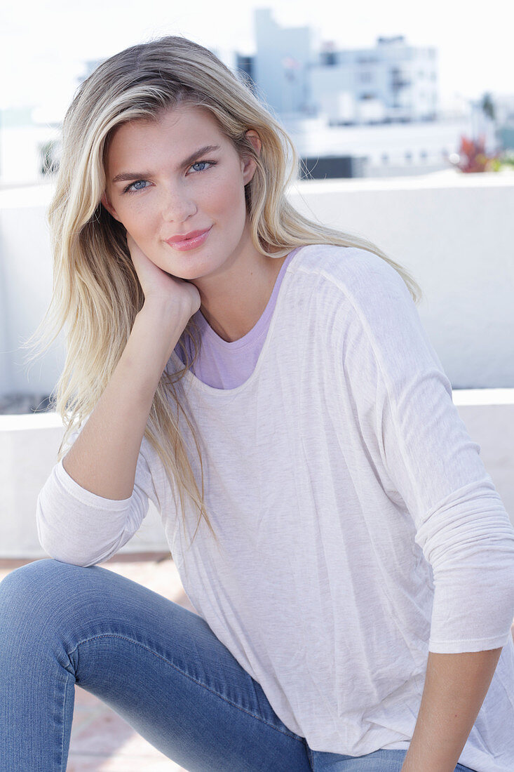 A young blonde woman wearing a purple t-shirt and a white jumper