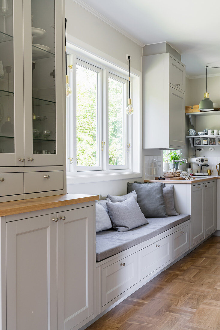 A built-in bench in front of the window in a bright kitchen