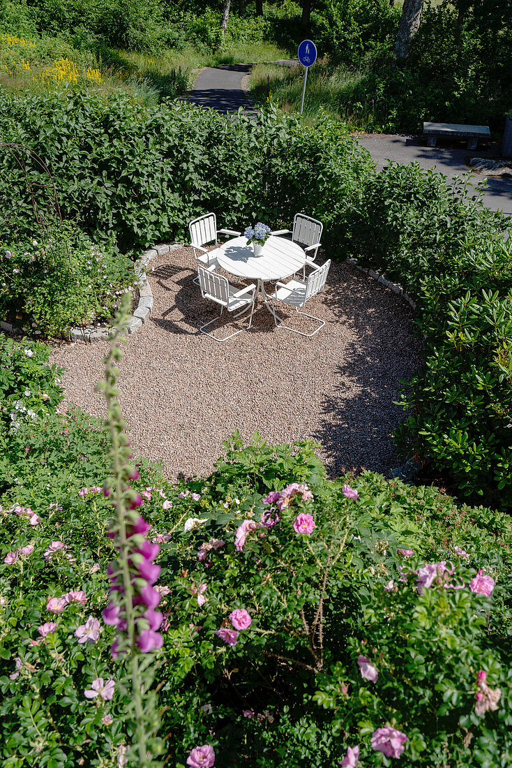 Terrassenplatz mit rundem Tisch und Stühlen in sonnigem Garten