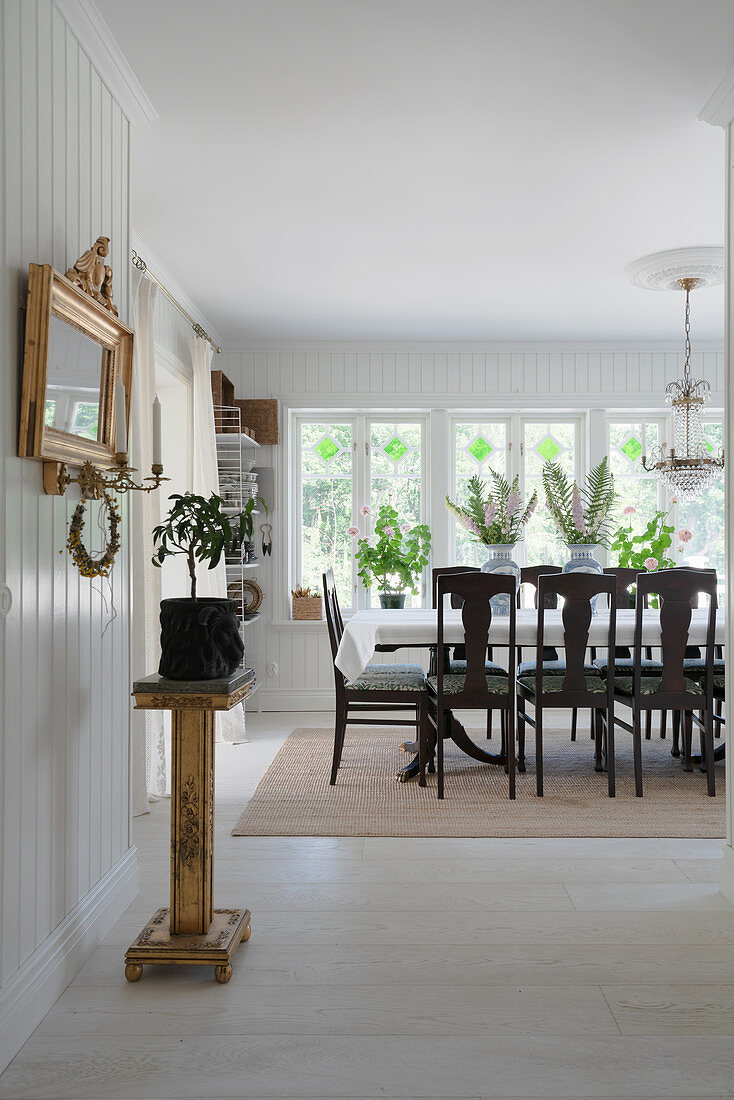 An antique stela and a gold-framed mirror with a dining area in the background