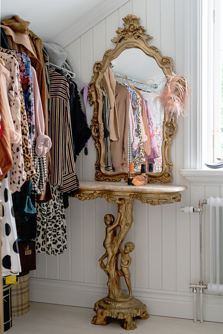 A gilded dressing table with a marble top and a mirror in a dressing room