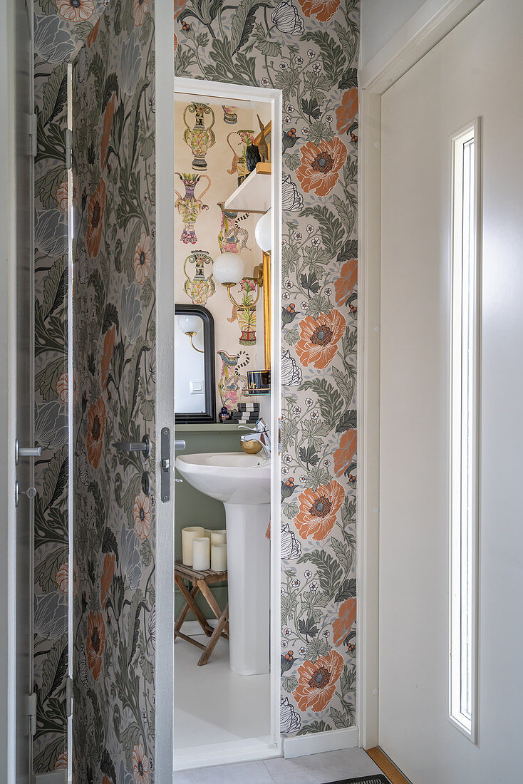 A view of a pedestal washbasin in a wallpapered guest toilet