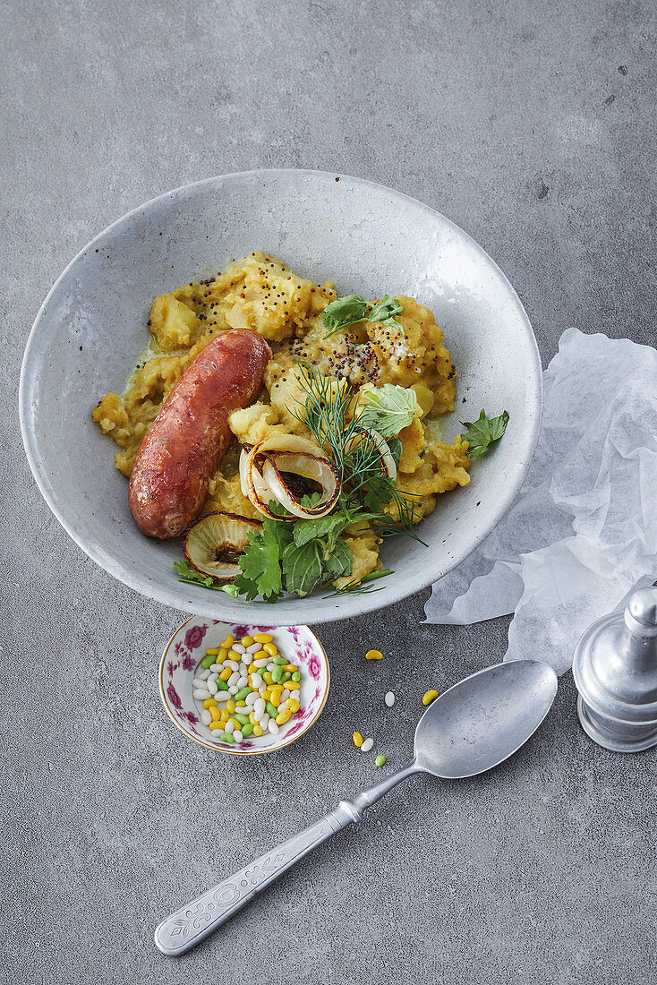 Sausages with fried onions on masala mashed potatoes and herb