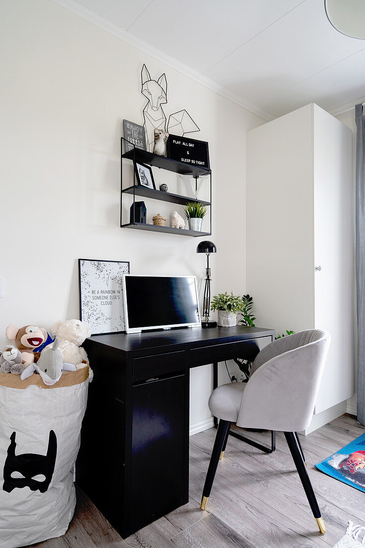 A dark desk, an upholstered chair and a sack of toys