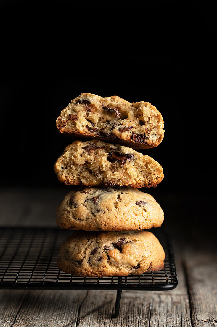 Stack of tasty cookies with chocolate placed on wooden table on black background