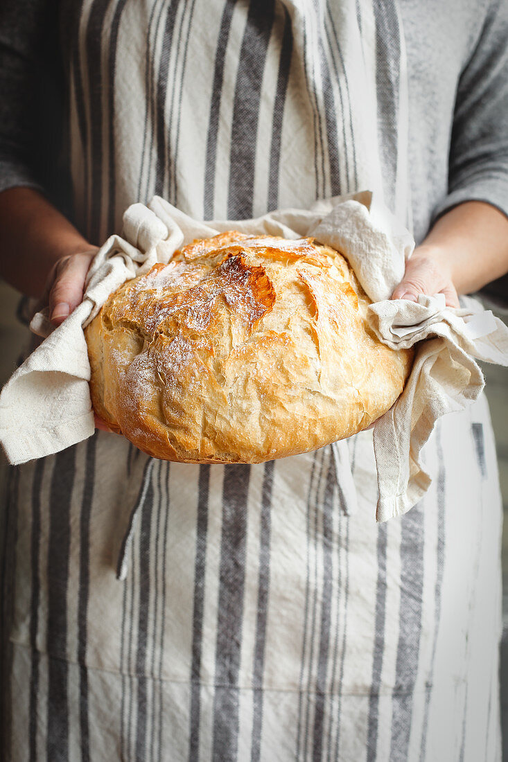 Frau hält frisch gebackenes Artisanbrot in den Händen