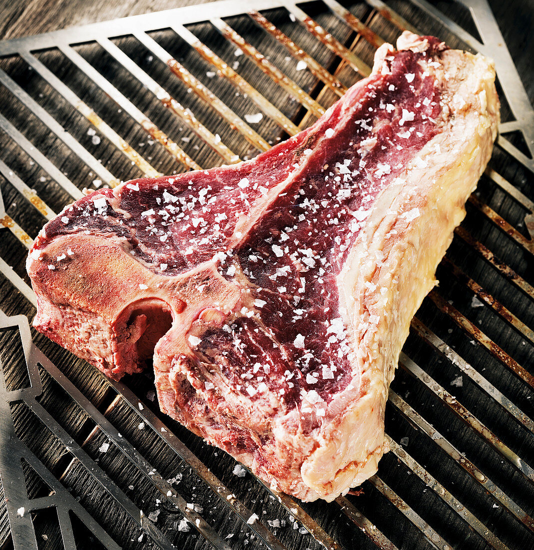 Rohes Porterhouse-Steak mit grobem Meersalz auf Grillrost
