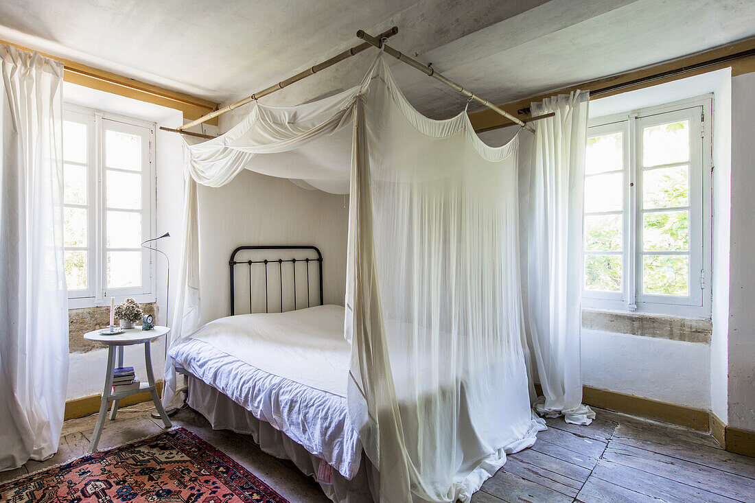 Bett mit Vorhang im Schlafzimmer mit rustikaler Holzdielenboden