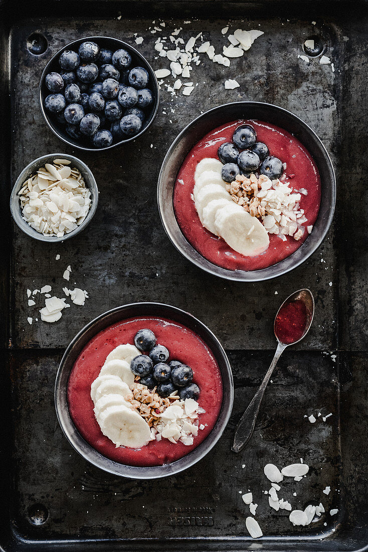 Raspberry smoothie bowl with blueberry banana and almond flakes