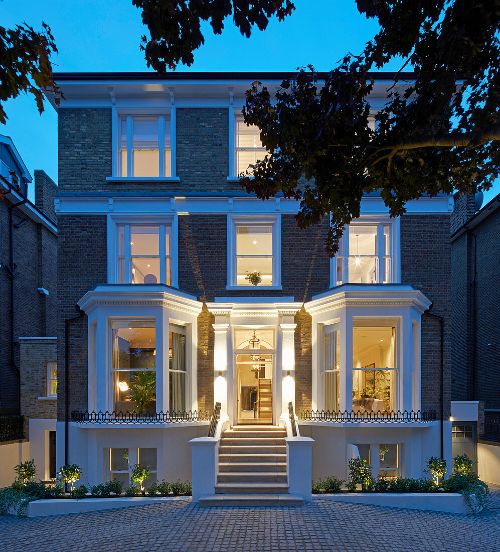 Classic, English-style house with bay windows illuminated at twilight