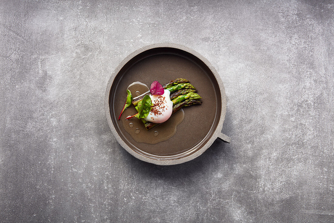 Green asparagus in vegetable consommé with a black tea broth and a sous vide egg