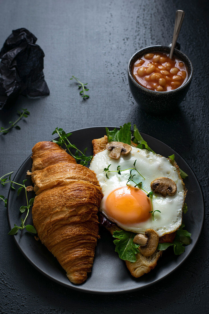 Croisant with fried egg, mushrooms, beans and grean leaves