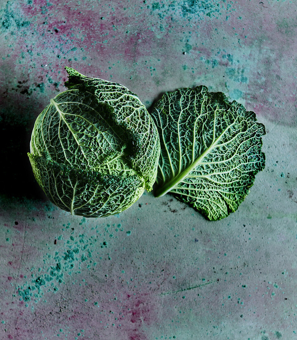 A Savoy cabbage on a green concrete surface